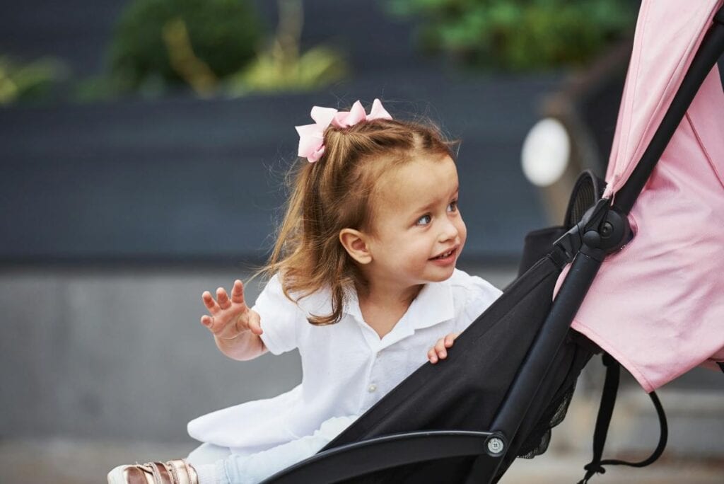 girl with bows in hair sitting in stroller