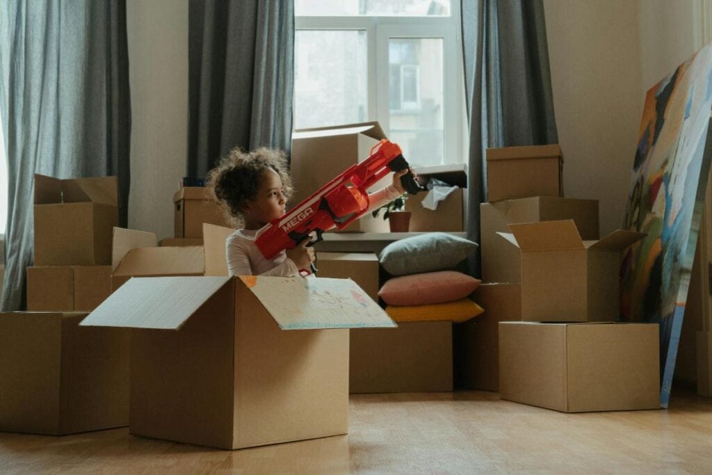 girl playing with toys in empty moving box