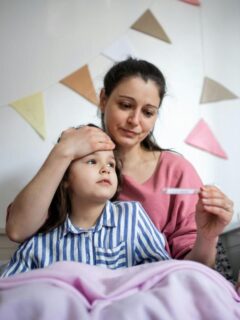 mom checking sick daughter's temperature