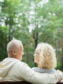 senior couple sitting on bench together outdoors enjoying reitrement
