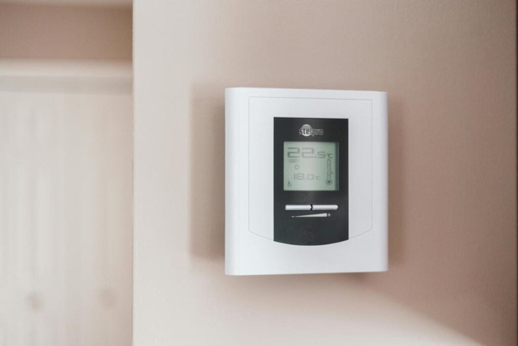Close-up of a digital thermostat mounted on a wall displaying indoor temperature settings for home comfort and energy savings.
