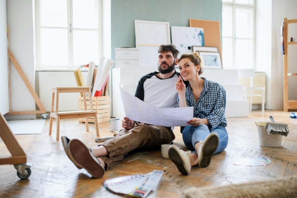 couple sitting in floor looking at blueprints or building plans
