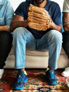 friends sitting on couch watching baseball game