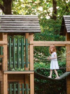 little girl walking across large backyard playset