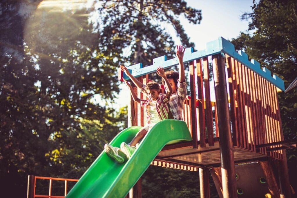 kids going down slide on playset