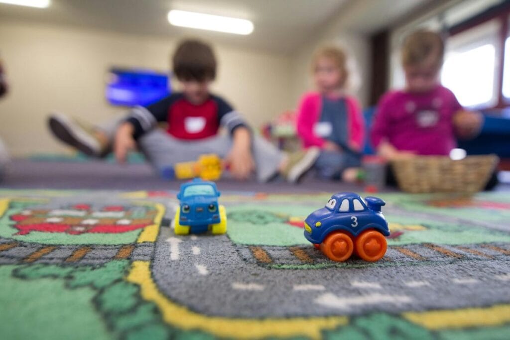 kids playing in background and small car toys in foreground