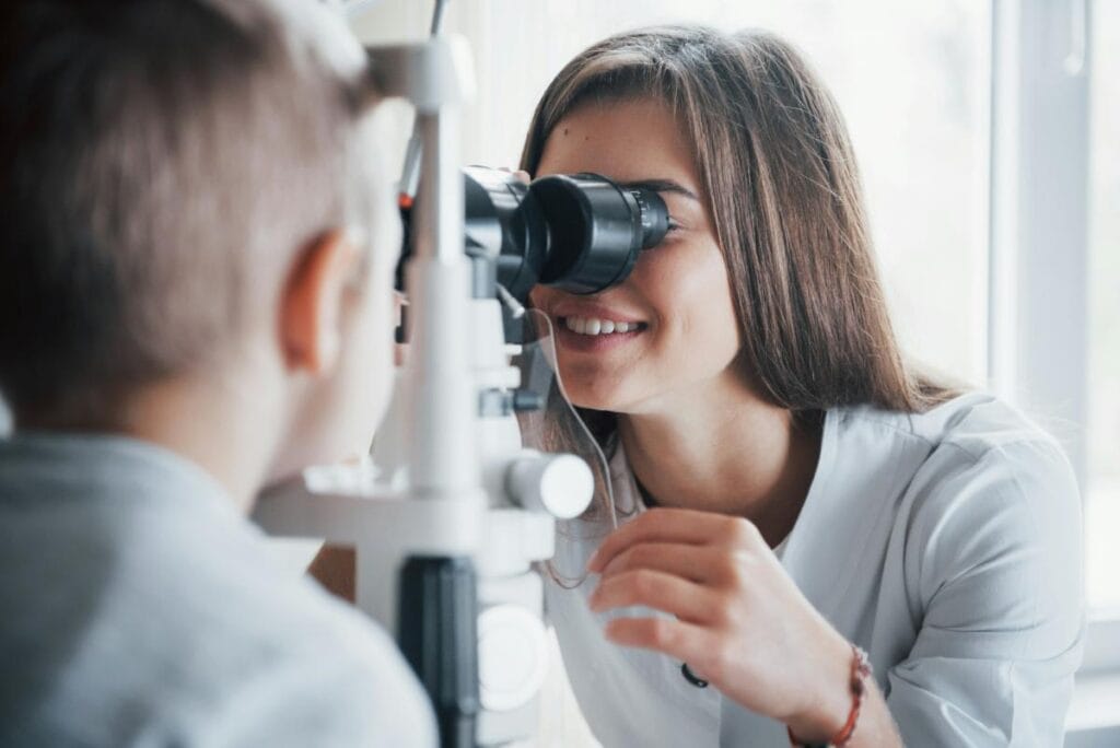 female eye doctor giving a little boy an eye exam