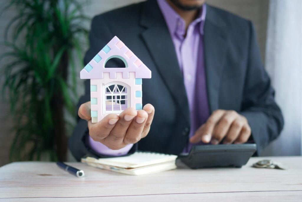person in suit holding a model of a house to represent getting a mortgage