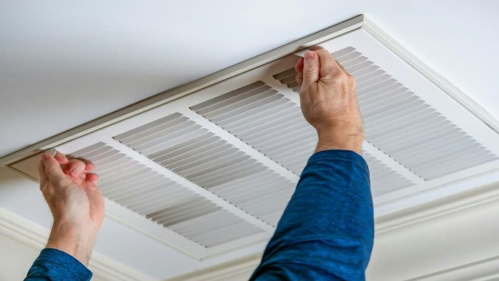 person replacing HVAC filter in ceiling