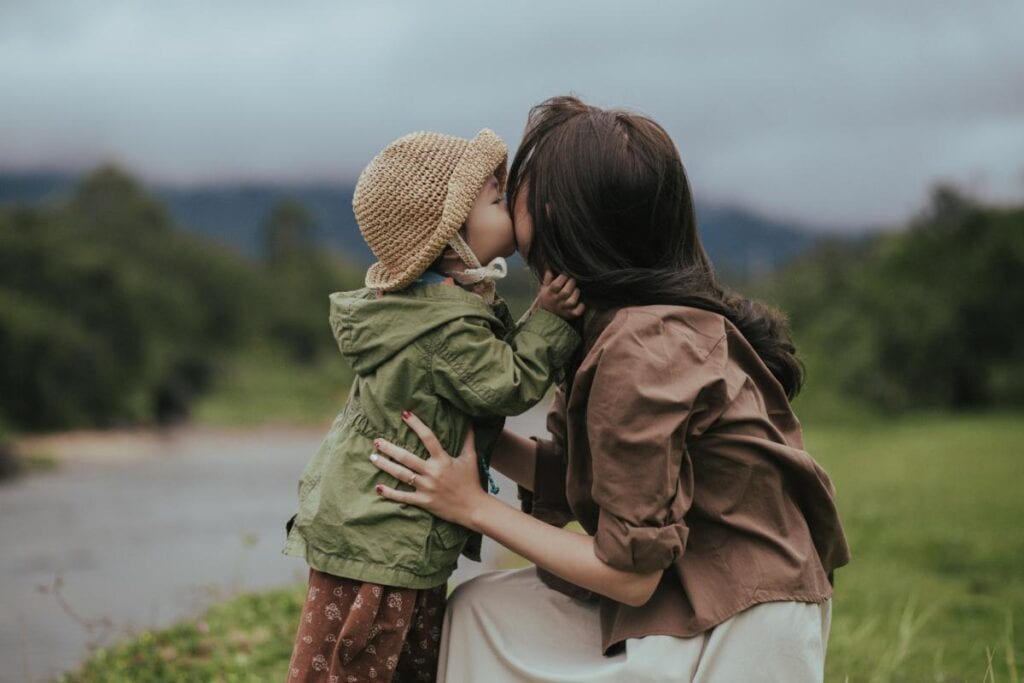 toddler kissing mother's cheek outdoors