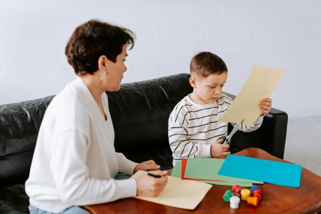 Child completing a guided craft activity with therapist support during an ABA therapy session designed to build independence and following directions.