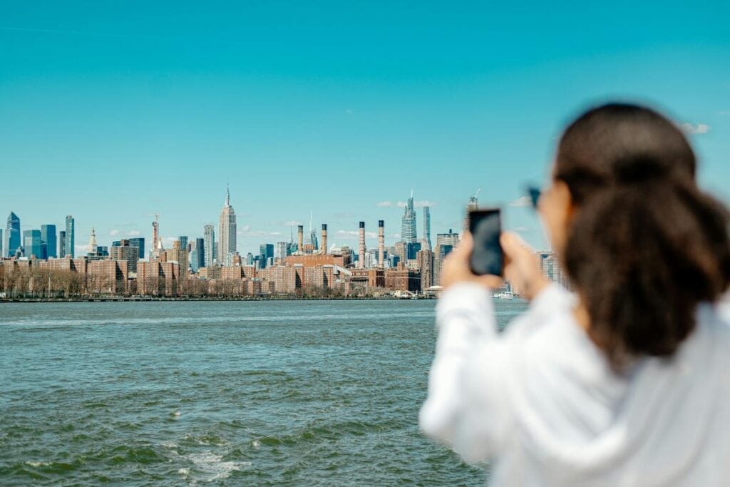 woman taking picture of nyc skyline on cell phone