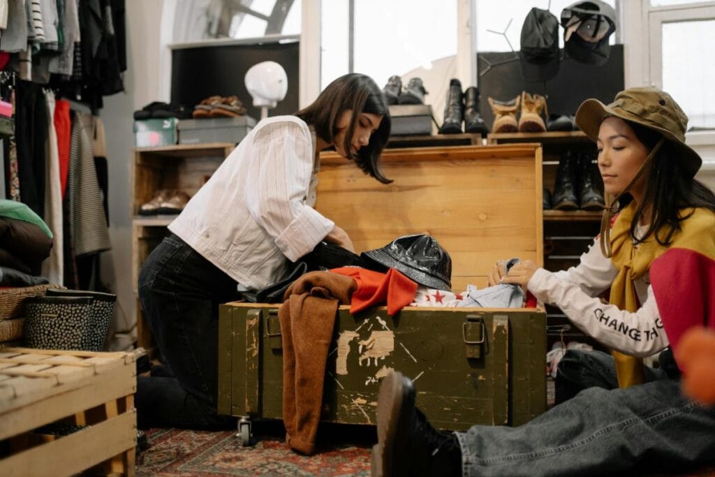two young women going through clothes in wooden trunk