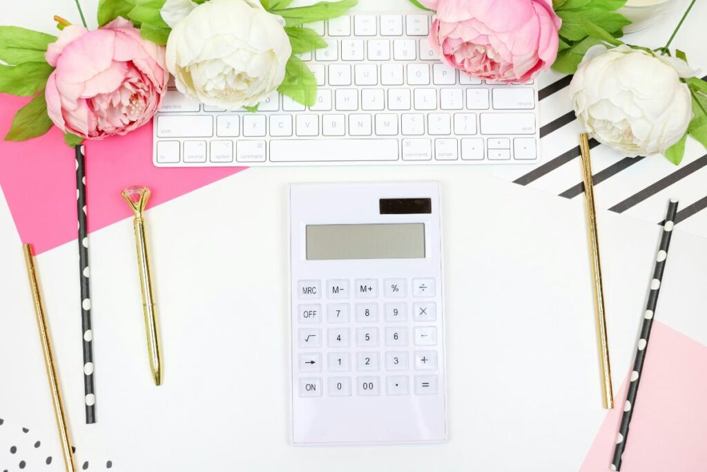 Calculator, keyboard, flowers, and stationery on a bright workspace, symbolizing budgeting, expense tracking, and financial organization for creators and small business owners.