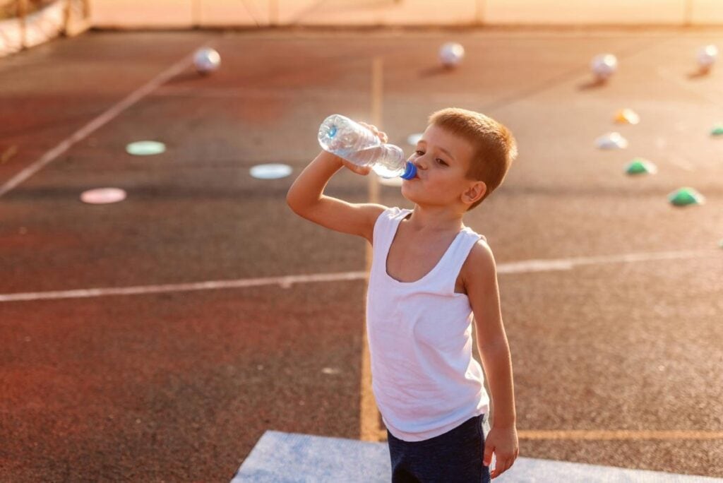 little boy drinking water on hot summer day