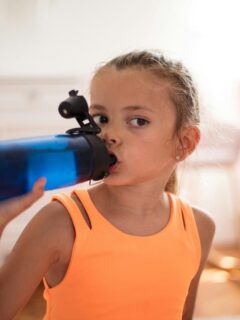 little girl drinking from blue water bottle