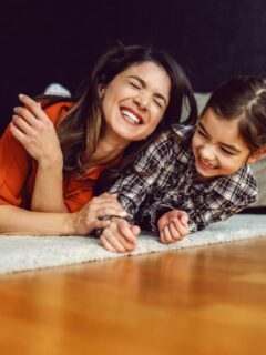 mom and daughter laying in floor laughing