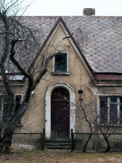 Vacant aging home with peeling roof and bare trees, symbolizing an inherited or unwanted property in need of attention.