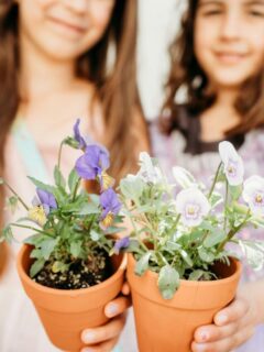 two girls holding flowers in pots