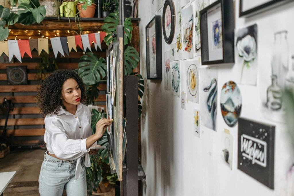 woman putting up art for display
