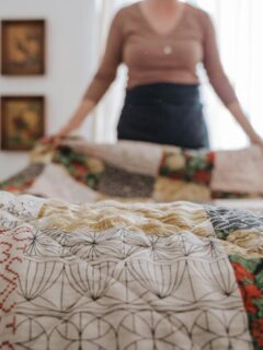 woman placing quilt on bed