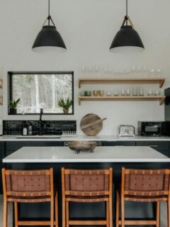 Modern family kitchen with a large island, black range hood, and open shelving.
