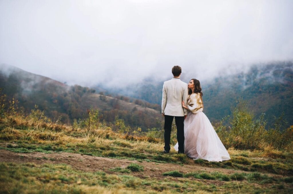 bride and groom posing in mountain landscape on foggy day