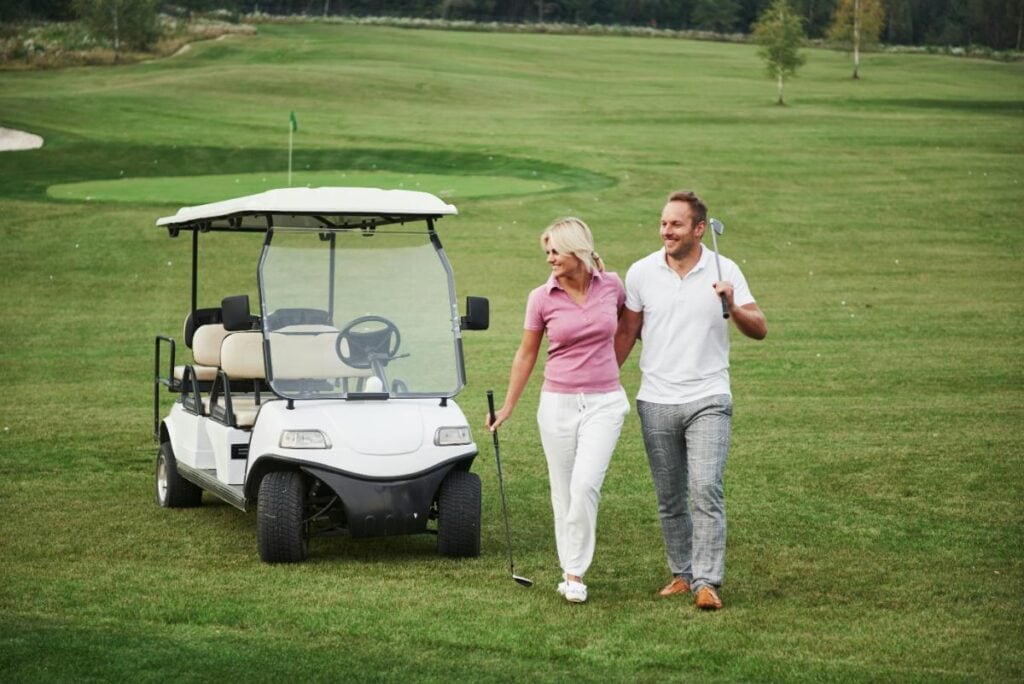 couple on a golf course with a golf cart