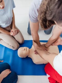 Group participating in a hands-on CPR training session using an adult mannequin.