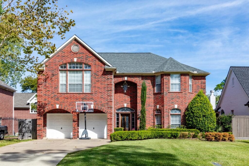 Large brick home with a well-maintained lawn, highlighting the importance of regular home maintenance and exterior inspections.