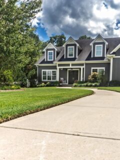 Well-maintained home with a landscaped yard and clean driveway, representing proactive home maintenance to prevent costly repairs.