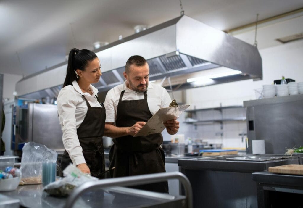 man and woman having discussion in restaurant kitchen