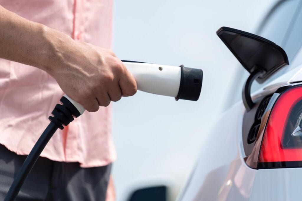 Driver plugging an electric car into a dedicated EV charger.