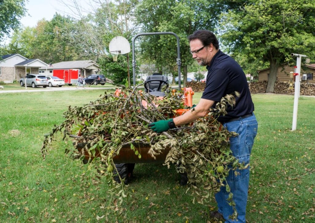 Grounds maintenance worker clearing tree branches to keep a property safe and well maintained.