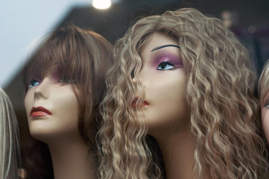 Mannequins showcasing different wig styles and textures for hair replacement options.