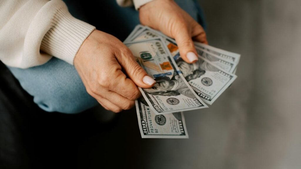 Close-up of hands counting cash, symbolizing careful financial planning, budgeting, and preparing for a responsible borrowing decision.