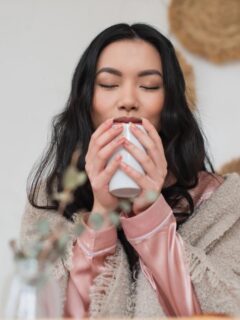 woman waking up in morning holding coffee while still wearing pajamas