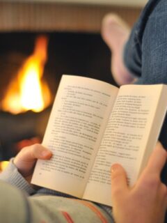 woman reading a book by the fireplace