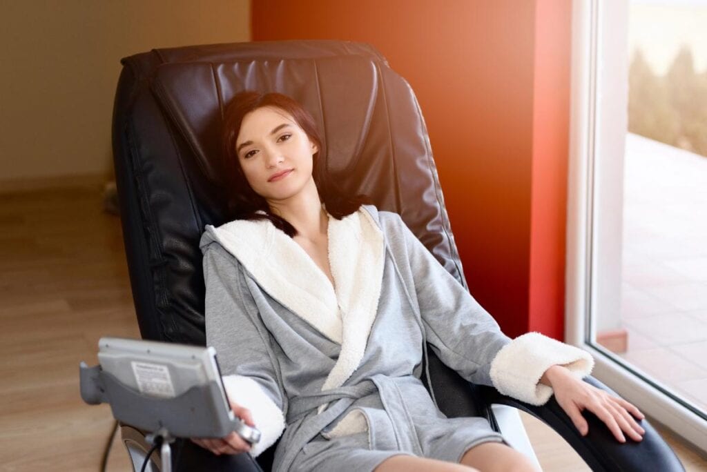Woman relaxing in a reflexology massage chair at home.