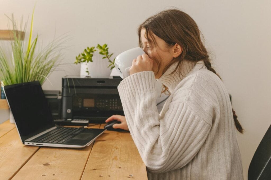 woman drinking coffee working from home office
