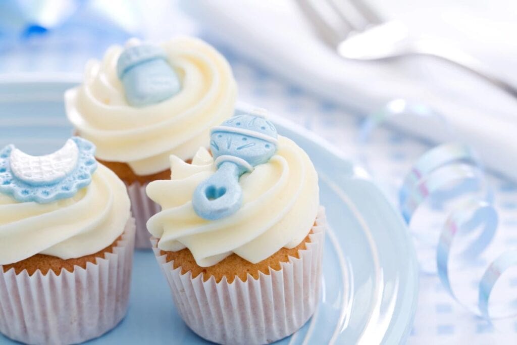 Baby shower cupcakes decorated with blue baby-themed toppers.