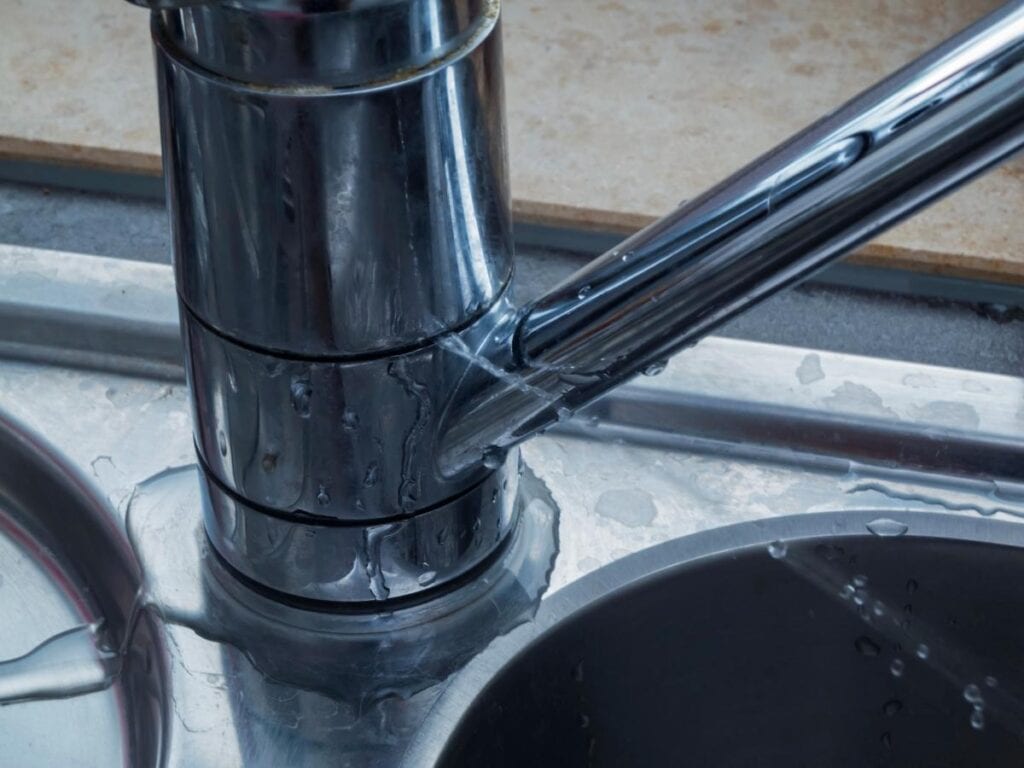 Leaking kitchen tap causing water damage around the sink.