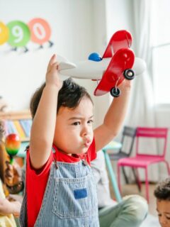 Preschool child using imaginative play with a toy airplane.