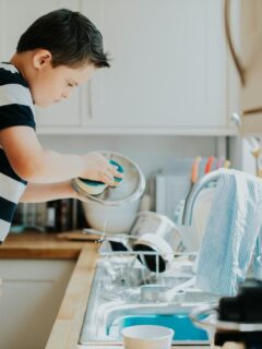 boy washing dishes to help keep the house clean