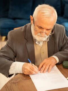 Senior man signing legal documents related to a will.