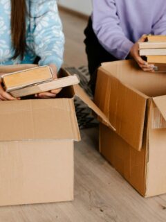 People packing books into boxes for donation during a house cleanout.