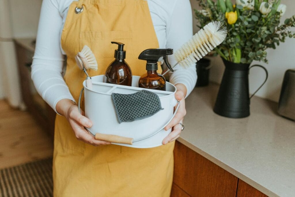 Person holding eco-friendly cleaning supplies while preparing for a home cleanout.