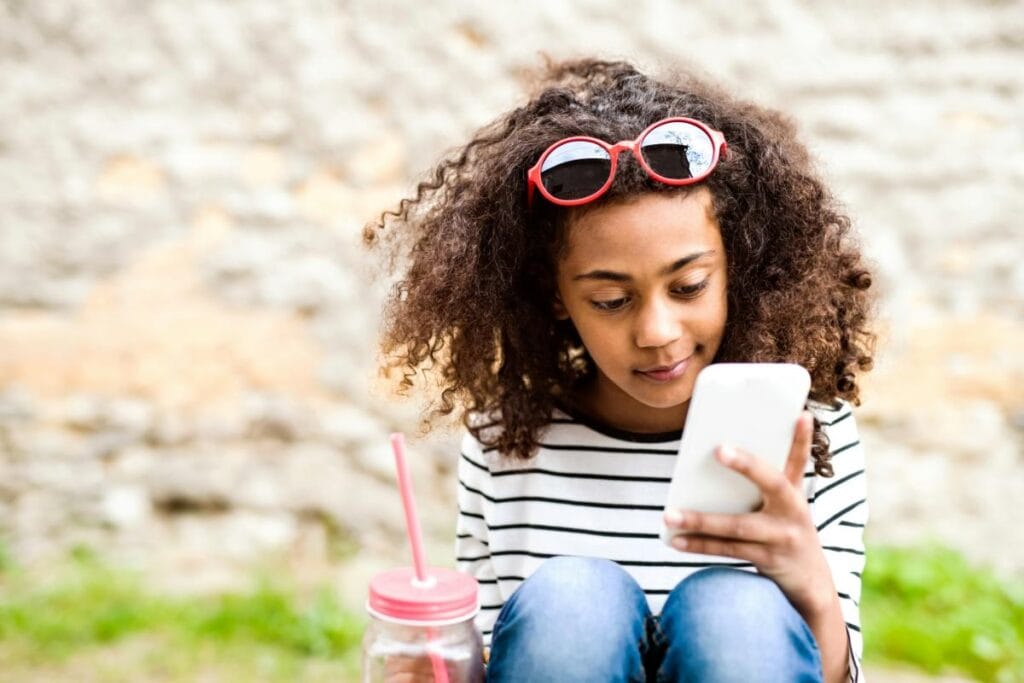 Child using a smartphone while sitting outdoors.