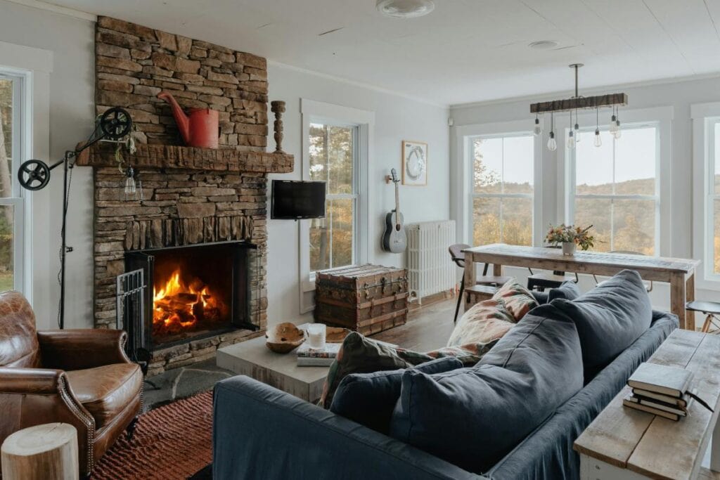 Cozy living room with a navy sofa, leather chair, and stone fireplace