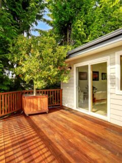 Sunny wood deck with railing, planter, and sliding glass door.